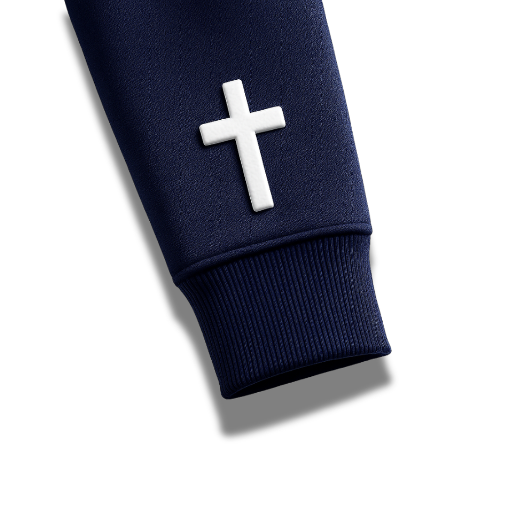 Close-up of navy blue Savior Brand hoodie sleeve featuring white embroidered cross detail near cuff. 